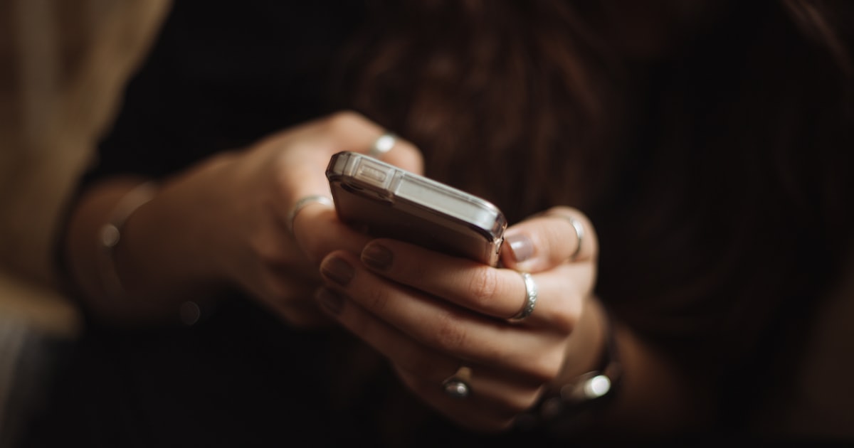 Mão segurando o celular com uma conversa aberta, como um paciente falando com a clínica pelo WhatsApp