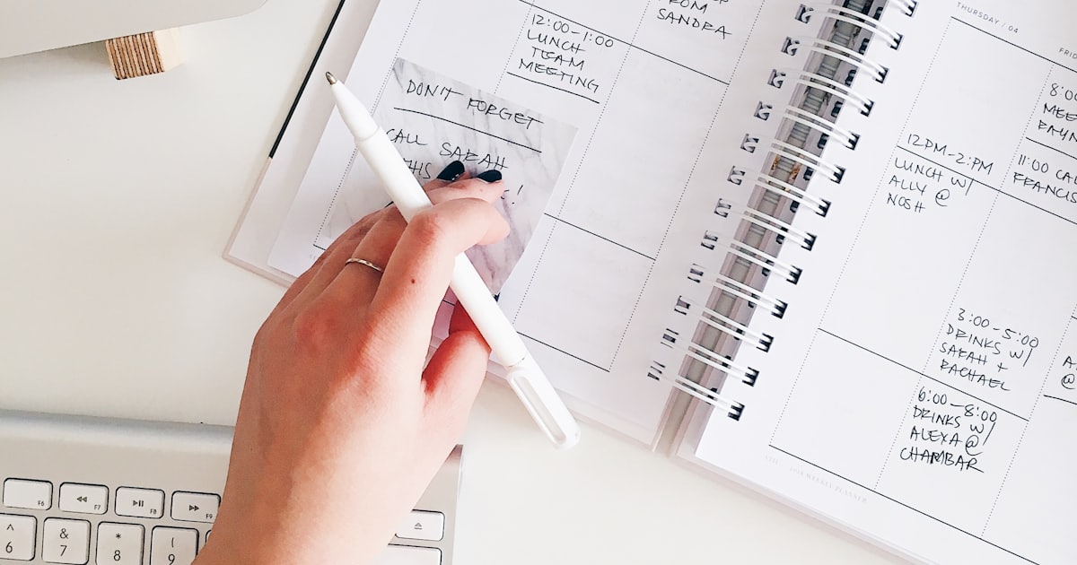 Mão preenchendo à caneta um caderno de anotações — o briefing do site da clínica