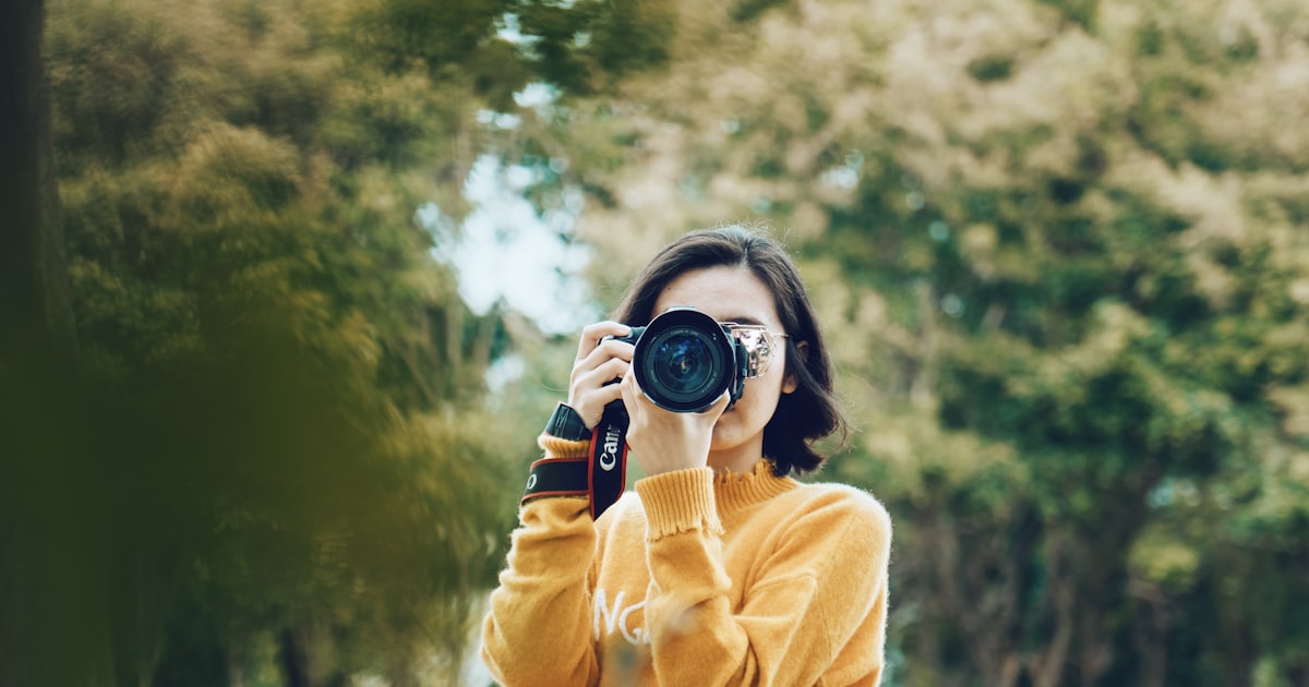 Mulher fotografando com câmera profissional — produção de fotos reais para o site