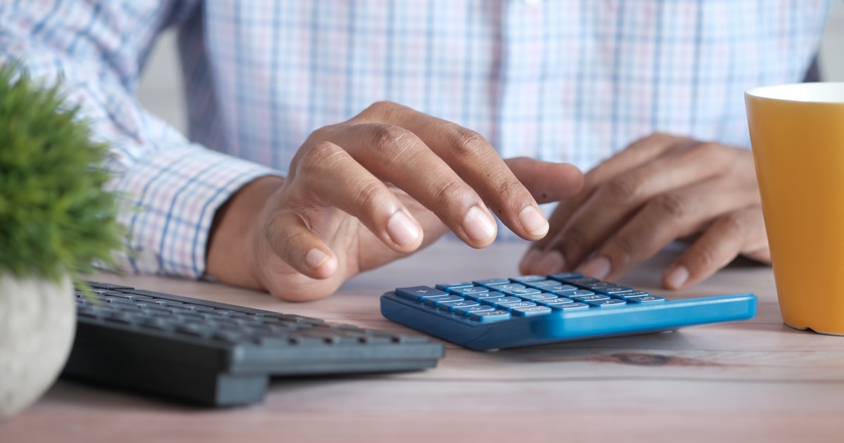 Mãos usando uma calculadora sobre a mesa para orçar o site da clínica